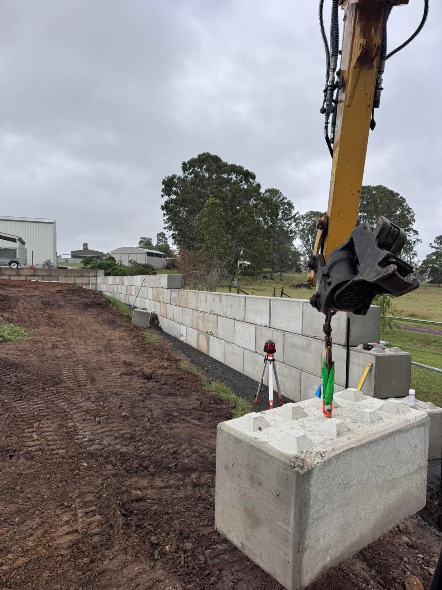 Concrete block retaining wall install with excavator